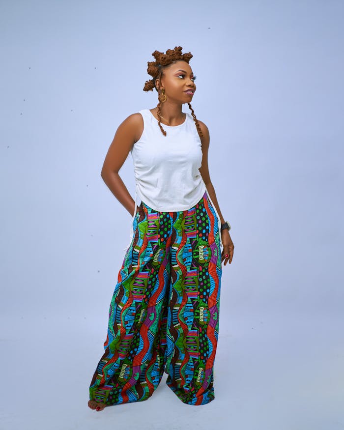 Fashionable woman posing confidently with unique hairstyle and vibrant patterned pants.